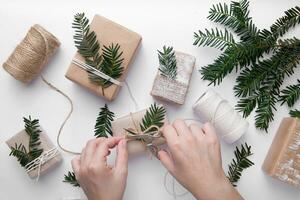 Christmas gifts wrapping ideas .Hand made gifts on white table with green decorations .Hands make easy brown paper gifts for Christmas photo