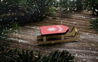 red wooden sled stand between fir branches. Christmas tree toys. concept for Christmas and new year holidays. snow falls.selective focus.High quality photo