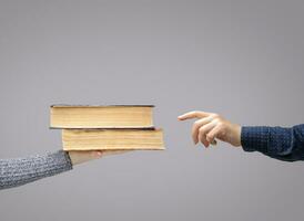 hand reaches for the books that lie on the palm of the invisible man. High quality photo