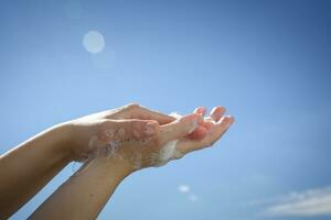 Closeup of Caucasian woman hands while washing hands with soap on blue sky background . Top view . Hygiene .Cleaning hands . Hygiene concept hand detail coronavirus protective measure photo