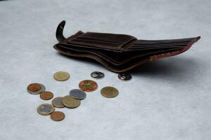 leather wallet from which small coins are poured onto a light table. selective focus photo