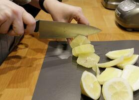 manos de un invisible hombre quien cortes un limón dentro rebanadas con un cuchillo.selectivo enfocar. alto calidad foto