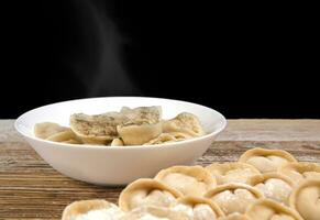 plate of homemade dumplings, and not boiled standing on the board. selective focus . photo