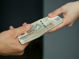 male and female hands holding a bundle of 200 zloty banknotes. selective focus photo