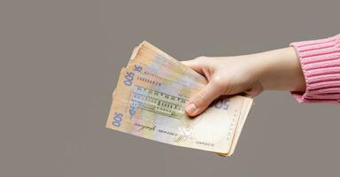 the girl hand holds bills of large denomination of the Ukrainian bank on a grey background. selective focus . High quality photo