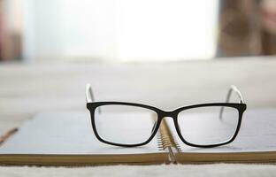 Image of an open notebook placed in bed with glasses at the top and a window in the background.blurred background. High quality photo