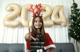 Asian woman dressed as a shanty Have fun celebrating Christmas 2024. Decorate and decorate the room with a Christmas tree and 2024 balloons. photo