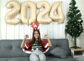 Asian woman dressed as a shanty Happy waiting to celebrate Christmas 2024. Decorate and decorate the room with Christmas tree and 2024 balloons. photo