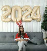 Asian woman dressed as a shanty Waiting time to wait to celebrate Christmas 2024. Decorate and decorate the room with Christmas tree and balloons 2024. photo