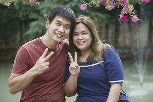 asian couples hand sign victory with happy smiling face photo