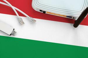Hungary flag depicted on table with internet rj45 cable, wireless usb wifi adapter and router. Internet connection concept photo