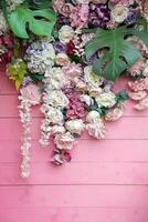 Floral background. Lot of artificial flowers in colorful composition on handmade wooden pink background photo