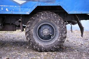 Wheel closeup in a countryside landscape with a mud road. Off-road 4x4 suv automobile with ditry body after drive in muddy road photo