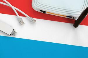 Luxembourg flag depicted on table with internet rj45 cable, wireless usb wifi adapter and router. Internet connection concept photo