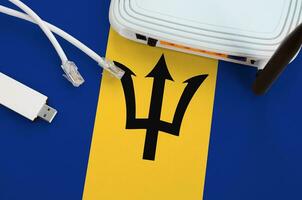 Barbados flag depicted on table with internet rj45 cable, wireless usb wifi adapter and router. Internet connection concept photo