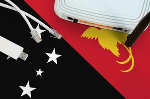 Papua New Guinea flag depicted on table with internet rj45 cable, wireless usb wifi adapter and router. Internet connection concept photo