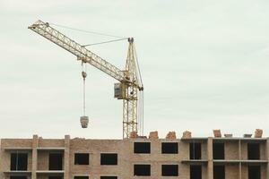 View of a large construction site with buildings under construction and multi-storey residential homes. Tower cranes in action on blue sky background. Housing renovation concept photo