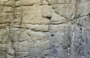 Light coarse natural rock stone background. Mining cliff rough front surface. Big limestone stack backdrop. Heavy grunge damaged granite block texture photo