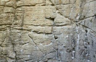 Light coarse natural rock stone background. Mining cliff rough front surface. Big limestone stack backdrop. Heavy grunge damaged granite block texture photo