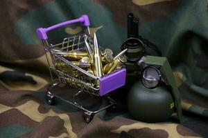 Rifle cartridges in small shopping cart. Big caliber ammo cartridges and hand grenades with a small shopping basket photo