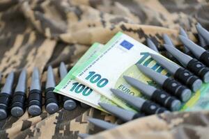 Bundles of euro bills and a machine gun belt on the camouflage uniform of a Ukrainian soldier. Concept of war financing, bribe or donation photo