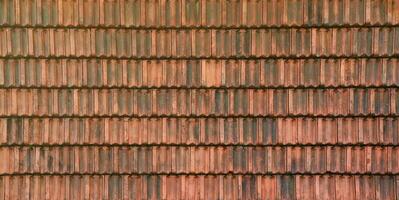 Close up of red terracotta roof shingles with some mildew. Background texture of roofing material photo