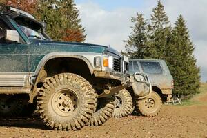 Automobile in a countryside landscape with a mud road. Off-road 4x4 suv automobile with ditry body after drive in muddy road photo