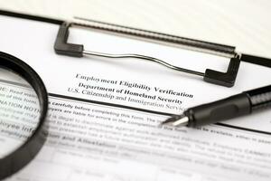 I-9 Employment Eligibility Verification blank form on A4 tablet lies on office table with pen and magnifying glass photo