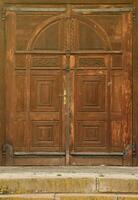 Very old solid wooden door in retro 19th century design close up photo