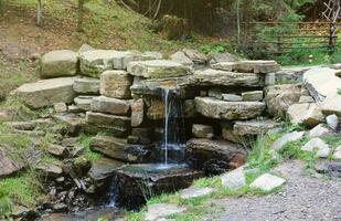 Close up of a small waterfall spilling over moss covered rocks in regional park. Handmade river waterfall photo