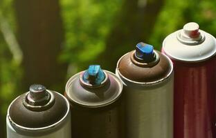 A few used aerosol paint sprayers lie on the windowsill in the workshop of a graffiti artist. The concept of street art and illegal drawing on the walls. Youth hobby photo