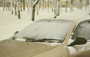 Fragment of the car under a layer of snow after a heavy snowfall. The body of the car is covered with white snow photo