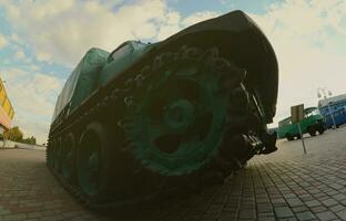 Photo of a Russian green armored car on a caterpillar track among the railway trains. Strong distortion from the fisheye lens