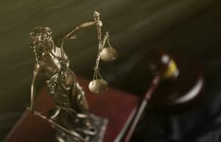 The Statue of Justice - lady justice or justitia the Roman goddess of Justice. Statue on brown book with judge gavel. Concept of judicial trial, courtroom process and lawyers work photo