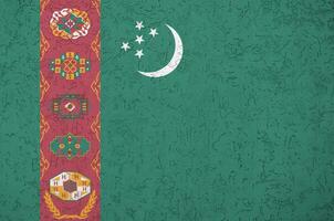 Turkmenistan flag depicted in bright paint colors on old relief plastering wall. Textured banner on rough background photo