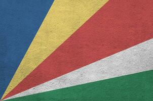 Seychelles flag depicted in bright paint colors on old relief plastering wall. Textured banner on rough background photo