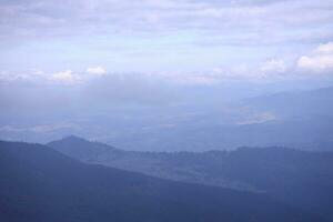 Morning view from the Dragobrat mountain peaks in Carpathian mountains, Ukraine. Cloudy and foggy landscape around Drahobrat Peaks photo