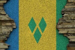 Saint Vincent and the Grenadines flag depicted in paint colors on old stone wall closeup. Textured banner on rock wall background photo