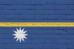 Nauru flag depicted in paint colors on old brick wall. Textured banner on big brick wall masonry background photo