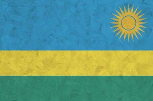 Rwanda flag depicted in bright paint colors on old relief plastering wall. Textured banner on rough background photo