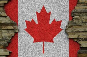 Canadá bandera representado en pintar colores en antiguo Roca pared de cerca. texturizado bandera en rock pared antecedentes foto
