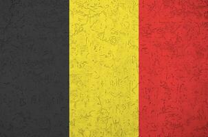 Belgium flag depicted in bright paint colors on old relief plastering wall. Textured banner on rough background photo