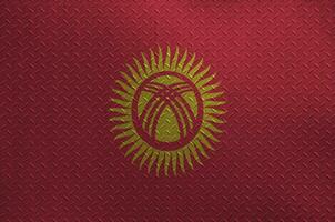 Kyrgyzstan flag depicted in paint colors on old brushed metal plate or wall closeup. Textured banner on rough background photo