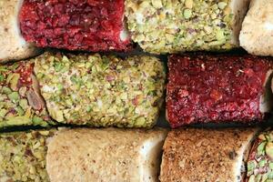 Rolls of turkish delight with many different flavors and fillings close up on table of vendors market photo