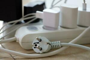 Overloaded power boards. Power strips with different electrical plugs on white floor photo