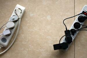 Overloaded power boards. Power strips with different electrical plugs on white floor photo