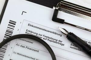 German annual income tax return declaration form blank on A4 tablet lies on office table with pen and magnifying glass photo