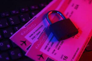 Fictional air tickets and small padlock on computer keyboard photo