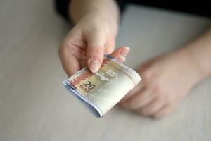 Brazilian money bills in woman hand. Female gives bunch of brazilian reais to us photo