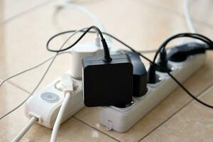 Overloaded power boards. Power strips with different electrical plugs on white floor photo